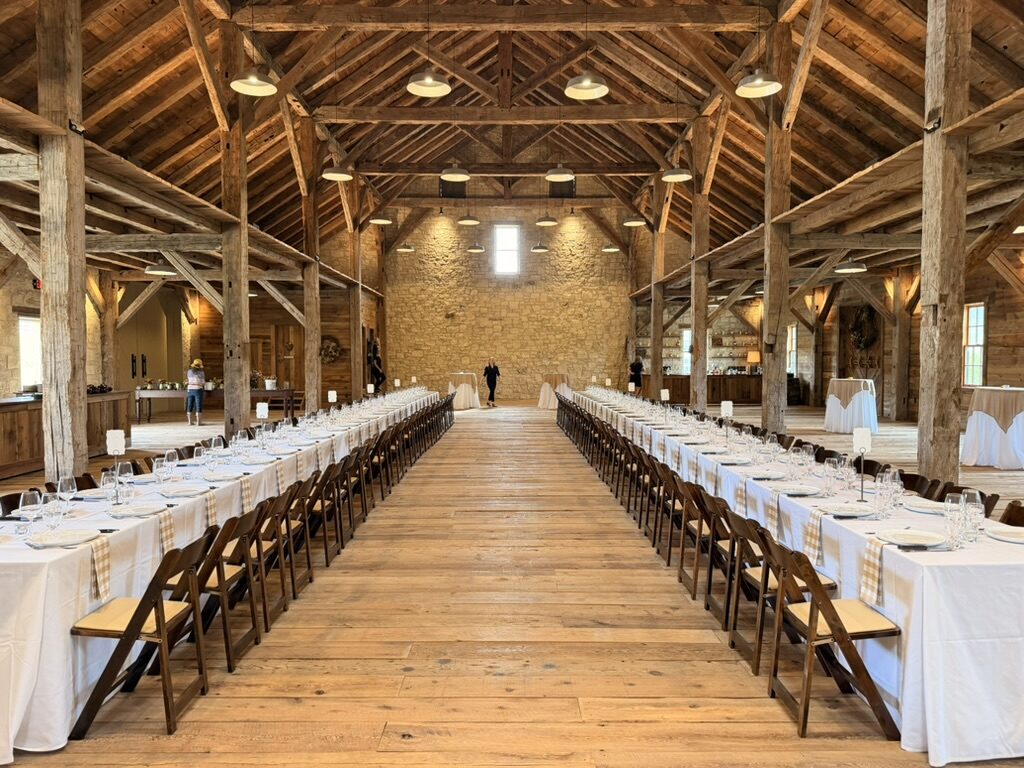 A timber barn set with long white tables for a banquet